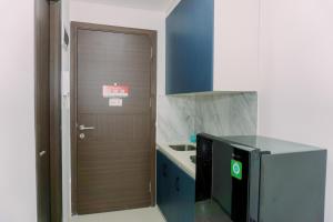 a small kitchen with a microwave and a door at Good Deal and Homey Studio Pacific Garden Apartment By Travelio in Tangerang