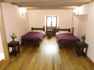 two beds in a room with wooden floors at OkiDoki Cusco Hostal in Cusco