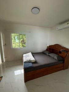 a bedroom with a wooden bed with a window at Silver Cliff Bungalow in Than Sadet Beach