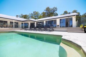 a swimming pool in front of a house at Nu Leaf Retreat in Pokolbin