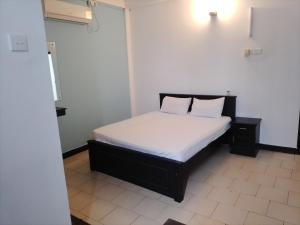 una camera da letto con un letto con lenzuola bianche e due cuscini di Akira Beach Hotel a Moratuwa