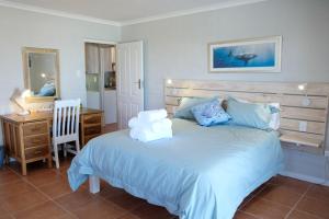 a bedroom with a large bed with a desk and a chair at Bayside Cottage in Cape Town