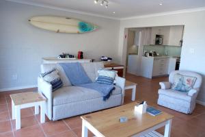 a living room with a couch and a surfboard on the wall at Bayside Cottage in Cape Town