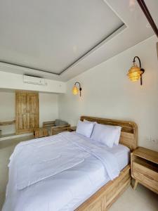 a bedroom with a large bed with white sheets at New Green Coco Villa in Amed