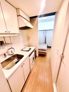 a small kitchen with white cabinets and a sink at Shinjuku West Park Inn Hanabi House in Tokyo