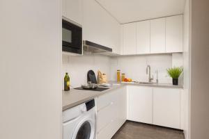 a kitchen with white cabinets and a washer and dryer at Somerset Wanxia Shenzhen in Shenzhen
