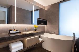 a bathroom with a tub and a sink and a mirror at Somerset Wanxia Shenzhen in Shenzhen
