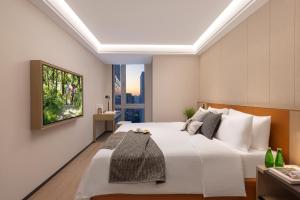 a bedroom with a large white bed and a window at Somerset Wanxia Shenzhen in Shenzhen