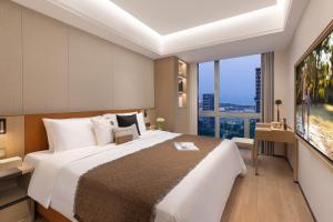 a bedroom with a large bed and a large window at Somerset Wanxia Shenzhen in Shenzhen