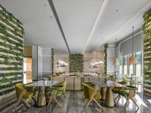 a dining room with tables and chairs and a kitchen at Hilton Shanghai Hongqiao International Airport in Shanghai