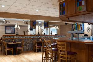 a restaurant with a bar with wooden stools at Wyndham Garden Otsego-Minneapolis in Otsego