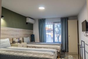 a bedroom with two beds and a window at Guest House Malusha in Gabrovo
