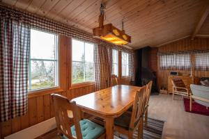 ein Esszimmer mit einem Holztisch und einigen Fenstern in der Unterkunft Trysilfjellet Nord 1017 in Trysil + 8 Fotos