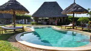 a swimming pool with umbrellas and a resort at MITI Beach Bungalows in Nungwi