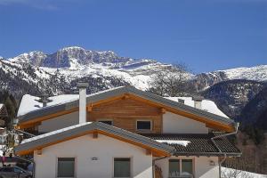 uma casa com montanhas cobertas de neve ao fundo em Dolomiti di Brenta House em Madonna di Campiglio