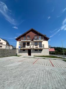 a large building with a large brick parking lot at Apartmán Všichni se vlezem in Kašperské Hory