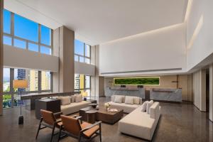 a living room with white furniture and large windows at Somerset Wanxia Shenzhen in Shenzhen