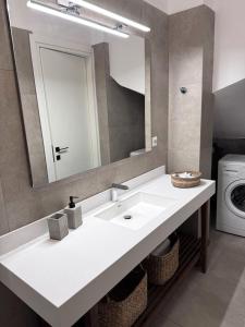 een badkamer met een witte wastafel en een spiegel bij Urban Nest Kalymnos in Kalymnos