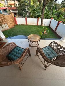 2 sillas de mimbre y una mesa en el patio en Ozzys Salt and Surf Haven, en Varkala