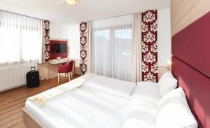 a bedroom with a large white bed and a desk at Kogler’s Pfeffermühle Hotel & Restaurant in Sankt Urban