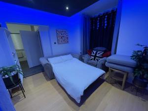 Habitación azul con cama y silla en Stylish 1 bedroom Flat Brixton, en Londres