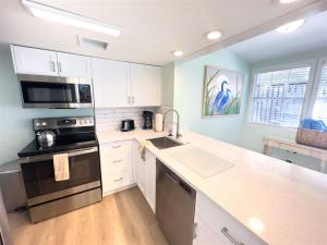 een keuken met witte kasten en een kookplaat oven bij Orange Blossom Suite Conch Republic Cottage in Key West