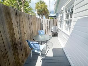 een terras met een glazen tafel en stoelen op een hek bij Orange Blossom Suite Conch Republic Cottage in Key West