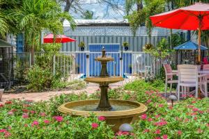 a fountain in the middle of a garden with pink flowers at Esperanza Suite in Key West