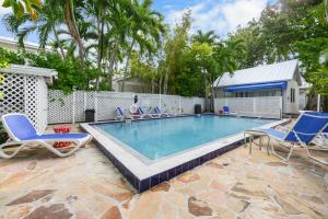 a swimming pool with blue chairs and a house at Colony Poolside in Key West