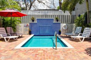 a swimming pool with chairs and a red umbrella at Bonaire Suite in Key West