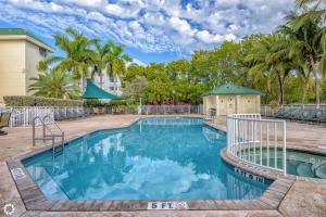 a swimming pool with blue water and palm trees at Sunrise Suite 203 in Key West