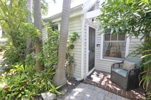 een veranda van een huis met een stoel en bomen bij Ann Street Cottage in Key West