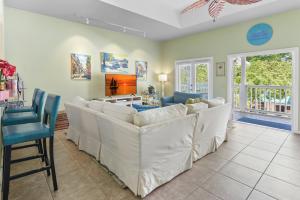 a living room with white couches and a television at Duval Square Courtyard Condo 31 in Key West