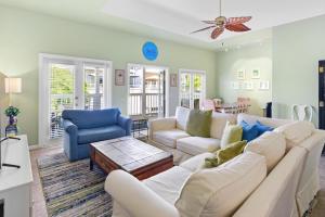 a living room with a white couch and blue chairs at Duval Square Courtyard Condo 31 in Key West