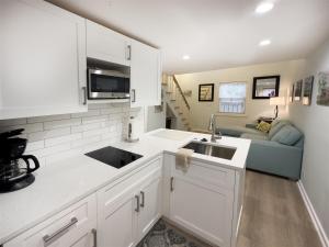 una cucina con armadi bianchi, lavandino e divano di Conch Republic Cottage a Key West