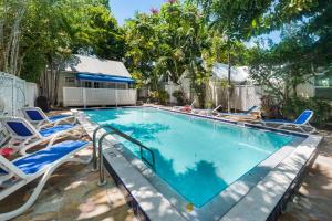 a large swimming pool with chairs and a house at Sunset Suite Colony in Key West
