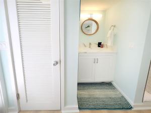 a white bathroom with a sink and a mirror at Deckside Suite Conch Republic Cottage in Key West