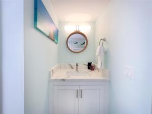 a white bathroom with a sink and a mirror at Deckside Suite Conch Republic Cottage in Key West