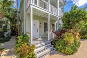 a green house with a white door and a porch at Windward Breeze in Key West