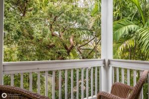 Dos sillas en un porche con vista a los árboles. en Windsor Townhomes 5, en Key West