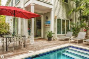 Un patio con mesa y sombrilla junto a una piscina. en Windsor Townhomes 5, en Key West