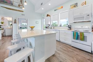 a white kitchen with white cabinets and a large island at Tiki Beach - Big Pine Key in Big Pine Key +25 photos