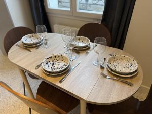 a wooden table with plates and wine glasses on it at Charming flat - 4 guests - 5 min from Metro and Canal in Pantin +11 photos