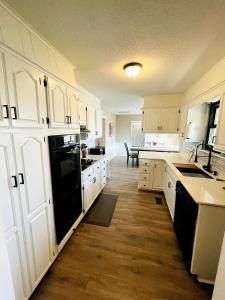 a kitchen with white cabinets and a black dishwasher at Full HOME with 2 KING BEDS and a POOL in Owasso