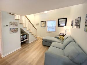a living room with a couch and a staircase at Porchside Paradise Conch Republic Cottage in Key West