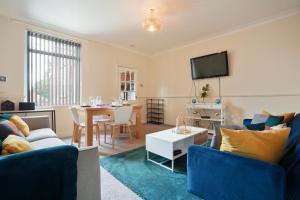 a living room with blue furniture and a dining room at HILLTOP PLACE SUITES 4 Bedrooms near PEAK DISTRICT in Killamarsh