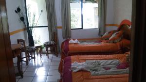 a room with three beds and a table and windows at Hotel Mixti in Cuetzalán del Progreso