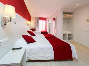 a bedroom with two beds with red pillows at Hostal Marino in San Antonio