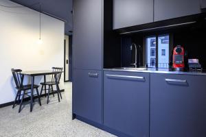 una cucina con lavandino e tavolo con sedie di BRIX - Self Check-In Hotel a Risch-Rotkreuz