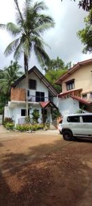 a car parked in front of a house with a palm tree at Star Rain Tour Inn in Ratnapura